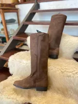 Bota alta de cuero marrón, con suela de goma y tira decorativa con hebilla metálica en la parte superior de la caña.