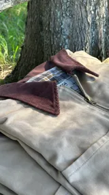 Campera de algodón color beige con cuello de pana en color chocolate. Presenta cierre frontal metálico y forro interior con estampado de cuadros.