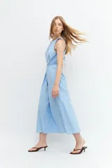 Maxi vestido celeste con rayas verticales blancas, cuello halter y lazo ajustable en la cintura.