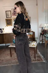 Pantalón de jean de corte recto y tiro medio, con un acabado de teñido ácido en tonos oscuros. Presenta bolsillos traseros con bordados decorativos en color negro y una etiqueta de cuero en la cintura.