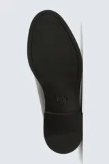 Zapato de vestir tipo oxford con puntera reforzada, confeccionado en piel lisa de color negro. Presenta cierre de cordones, forro interior y plantilla de piel, y suela con tacón bajo.