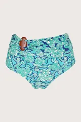 Calzón de bikini tiro alto con estampado floral en tonos celeste, azul y blanco. Presenta faja drapeada con accesorio decorativo de madera.