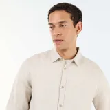 Camisa de lino de manga larga color beige, con cuello camisero y cierre frontal de botones.