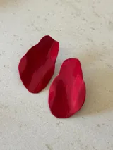 Par de aros colgantes rojos con forma irregular y superficie brillante.