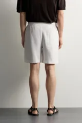 Bermuda de lino negro de corte relaxed fit, con cintura elástica ajustable mediante cordón y bolsillos frontales.