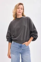 Buzo gris oscuro con efecto lavado, cuello redondo, hombros caídos y mangas abullonadas con puños ajustados.