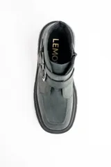 Bota corta de cuero lavado en tono gris oscuro, con suela track robusta y dos correas con hebillas metálicas en el lateral. Presenta un detalle de estrella metálica pequeña en la correa superior.