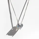 Collar plateado de cadena fina con dije de corazón blanco engarzado.
