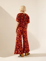 Pantalón de tiro alto y pata ancha con estampado floral en tonos naranja y borgoña. Presenta cintura de tela a tono con abertura lateral con cierre niquelado y tajos en el centro delantero.