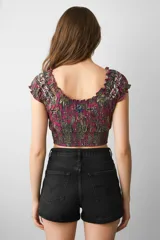 Top corto ajustado al cuerpo, con escote profundo en V y volados en los bordes. Presenta un estampado tipo paisley en tonos fucsia, verde oliva y azul oscuro. El cuerpo tiene frunces horizontales (smock).