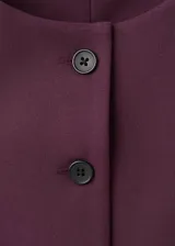 Chaleco bordó de cuello redondo y sin mangas, con cierre frontal de botones y diseño recto.