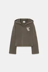 Sudadera de algodón color gris oscuro con capucha, manga larga y detalle de texto con aplicación de brillos en el pecho. Presenta un diseño con bolsillos laterales en las mangas y bajo recto.