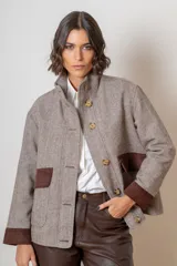 Campera de paño de lana color marrón con diseño oversize. Presenta cuello alto, cierre frontal con botones y detalles en pana azul marino en los puños y en las tapas de los bolsillos frontales.