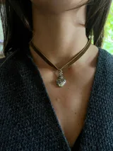 Gargantilla tipo choker con cinta de terciopelo rojo y dije metálico en forma de Sagrado Corazón con cruz superior.