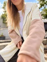 Campera con capucha de calce amplio, diseño en bloques de color beige, rosado y marrón, con aplique textil en la espalda que simula un paisaje montañoso. Cuenta con cierre delantero y bolsillos.