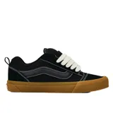 Championes Vans modelo Knu Skool, de diseño inspirado en los años 90 con silueta voluminosa. Presentan capellada de gamuza negra con lengüeta y cuello acolchados, Sidestripe en relieve 3D y suela de goma color caramelo con patrón waffle.