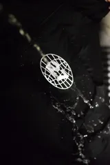 Campera puffer negra con capucha y cierre frontal. Tiene un logo estampado en el pecho.