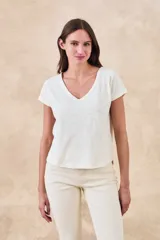 Remera de algodón color blanco hueso, con escote en V y manga corta. Presenta un ligero efecto jaspeado en la tela.