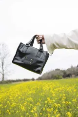 Mini bag negra de cuero charol con doble asa corta y detalles de costuras en color tostado.