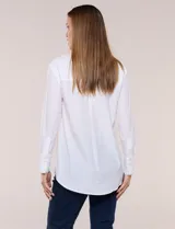 Camisa de calce relajado color celeste, confeccionada en tejido de textura suave y fluida. Presenta cuello camisero y abotonadura frontal, mangas largas con puño ancho y ruedo curvo.