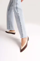 Chatitas de cuero con diseño bicolor, combinando tonos chocolate y off-white. Presentan una silueta de punta fina y un taco bajo de bloque.