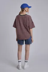 Remera oversize a rayas horizontales en tonos bordó y blanco, con cuello redondo verde oscuro y un pequeño parche bordado en forma de corazón en el pecho.