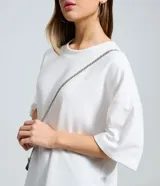 Remera oversize blanca de manga corta, con cuello redondo y diseño holgado, confeccionada en mezcla de algodón y poliéster.