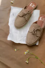 Mules de gamuza color tostado con diseño de zapato náutico, con cordones frontales y plantilla con logo estampado.