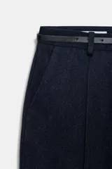 Pantalón tobillero de corte recto en color beige, con detalle de nervio delantero marcado. Incluye cinturón fino, bolsillos delanteros y cierre frontal con cremallera, botón interior y gancho.