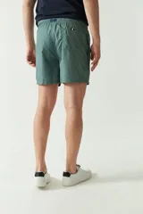Short de baño estampado con diseño geométrico en tonos verdes, cintura elástica con cordón ajustable, bolsillos laterales y bolsillo trasero.