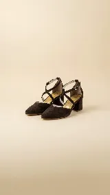 Zapato de tacón ancho de 5 cm, confeccionado en tela de tapicería resistente color marrón oscuro. Presenta un diseño con escote en V en la puntera y tiras cruzadas en diagonal con cierre de hebilla ajustable en el tobillo. Cuenta con forro y plantilla de cuero.
