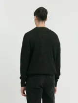 Sweater de punto con cuello redondo, manga larga y puños y ruedo acanalados. Presenta un diseño jaspeado en tonos oscuros.