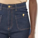 Pantalón de jean azul oscuro de corte recto y largo cropped, con diseño de tiro alto, bolsillos frontales tipo parche y cierre de botones metálicos.