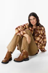 Bota corta de gamuza color chocolate, con suela track dentada y detalle de tira cruzada con apliques metálicos dorados.