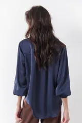 Camisa azul marino de satén con cuello clásico, cierre frontal con botones y mangas largas con puños abotonados.