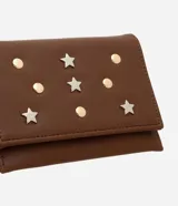 Billetera pequeña tipo sobre color marrón, confeccionada en cuero sintético. Presenta apliques decorativos metálicos en forma de estrellas y círculos en la parte frontal.