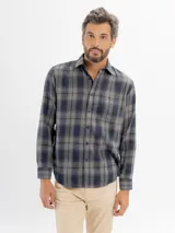 Camisa de franela a cuadros en tonos azul y negro, con cuello clásico, cierre frontal de botones y bolsillo en el pecho.