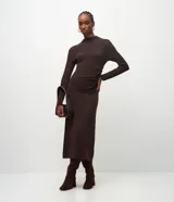 Vestido midi de punto color marrón chocolate, con manga larga, cuello alto sutil y detalle de fruncido lateral que ajusta la silueta. Diseño minimalista de corte recto.