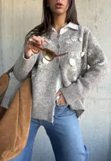 Cardigan de punto color beige con diseño de flores bordadas en relieve, cuello redondo, cierre frontal con botones y puños acanalados.