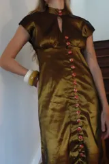 Vestido largo verde de tafeta con silueta entallada, cuello alto, mangas cortas, abertura tipo gota en el escote y hilera de botones frontal.