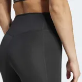 Calza deportiva negra de tiro alto y ajuste ceñido, confeccionada con tejido elástico y tecnología AEROREADY que absorbe la humedad. Presenta costuras selladas y un bolsillo oculto en el muslo.