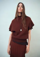 Falda larga de punto fino en color marrón chocolate, con diseño evasé y cintura elástica. Presenta un acabado con costuras verticales decorativas a lo largo de la prenda.