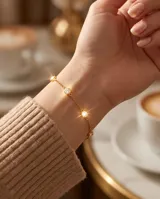 Pulsera de acero con baño de oro y dijes circulares con circonias engastadas.