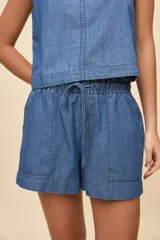 Short de calce relajado en denim azul, con cintura elastizada, cordón ajustable, bolsillos delanteros aplicados y ruedo ancho.