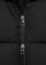 Campera puffer acolchada de color negro, con capucha, cuello alto, cierre de doble cremallera y bolsillos laterales.