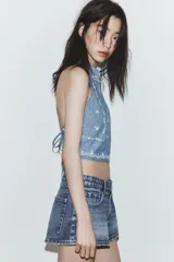 Top de cuello halter con escote en pico y cierre de botón. Presenta bordados florales a contraste y espalda descubierta con lazada.