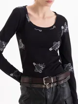 Remera de algodón negro con estampado de fresas y alfileres de gancho, de manga larga y escote redondo amplio.