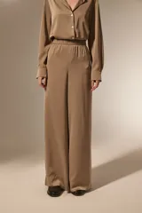 Pantalon de vestir de corte ancho y tiro alto, confeccionado en tela de viscosa con acabado satinado. Presenta cintura elástica y diseño fluido.