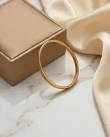 Pulsera tipo esclava rígida de acero con baño de oro, con diseño de líneas paralelas en relieve.