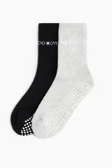 Pack de dos pares de medias deportivas de caña media, una negra y una gris melange, con puntos de agarre antideslizantes en la planta y texto impreso en la caña.